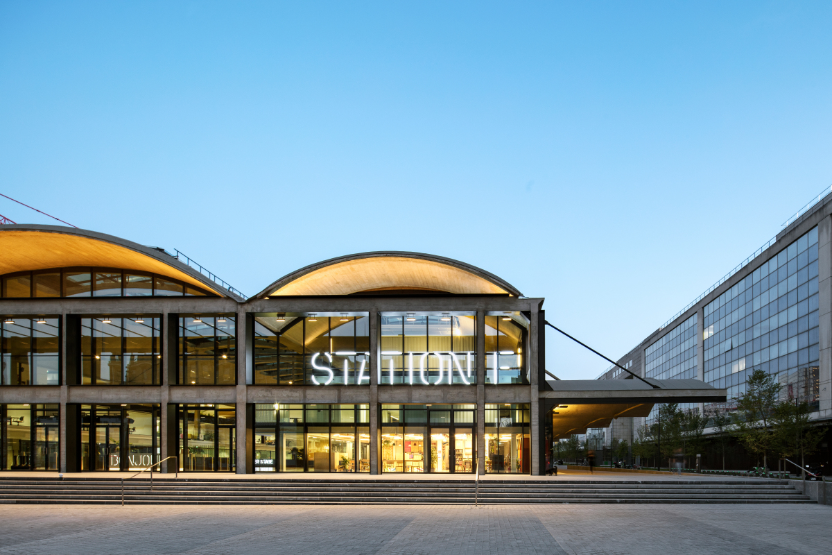 Facciata di Station F al crepuscolo, con l'insegna luminosa e le volte in cemento